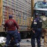 Les secouristes évacuent un corps sur le lieu de l'accident entre un bus à impériale et un train, sur un passage à niveau. KEYSTONE/AP/Ramses Mercado Valdes